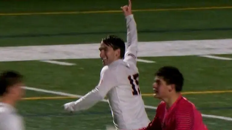 Eddie Zoeller secures the State Championship title for the Naperville North Huskies with kick as he runs on the field and holds up his hand.