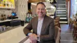 Jeremy Stolberg, CEO and Founder of Lennon's sits at the bar and smiles at the camera.
