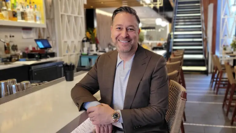 Jeremy Stolberg, CEO and Founder of Lennon's sits at the bar and smiles at the camera.