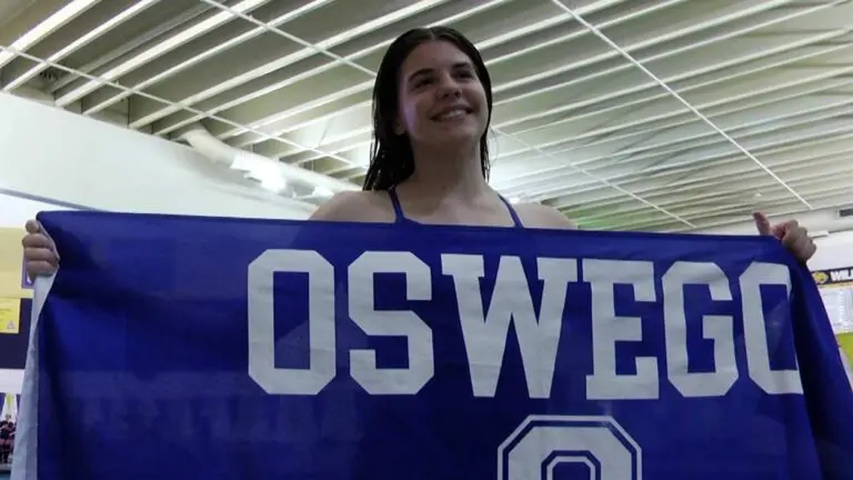 Oswego Co-Op takes top spot at diving sectional, as Katie Malm stands with the Oswego flag.