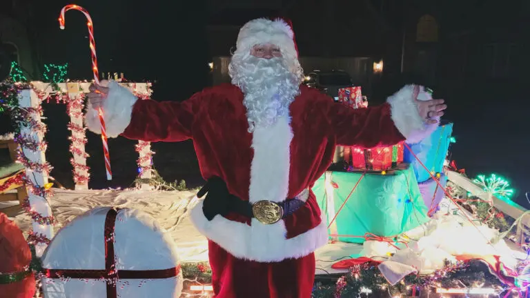 Santa Claus stands in front of his sleigh.