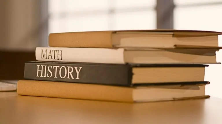 Close up of school books stacked with words Math and History on side of two books