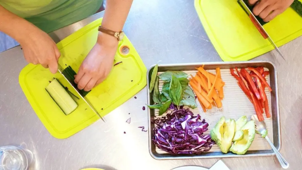 Guests at Taste Buds Kitchen cut up vegetables for a meal they are learning to cook.