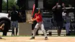 A Naperville Little League Baseball player in a red jersey is at bat.