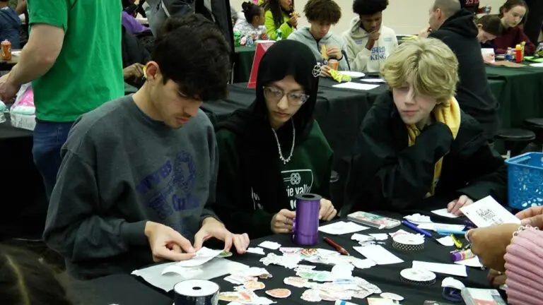 Three students look at a selection of stickers during the MLK Day of Service at Waubonsie Valley High School.