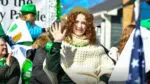 A Naperville St. Patrick's Day Parade participant smiles and waves at the camera.