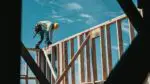 Construction worker on top of a wooden frame for a home