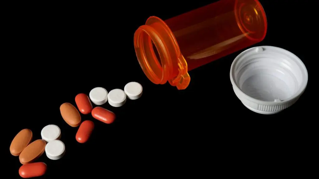 Pills spillilng out of pill bottle with black background