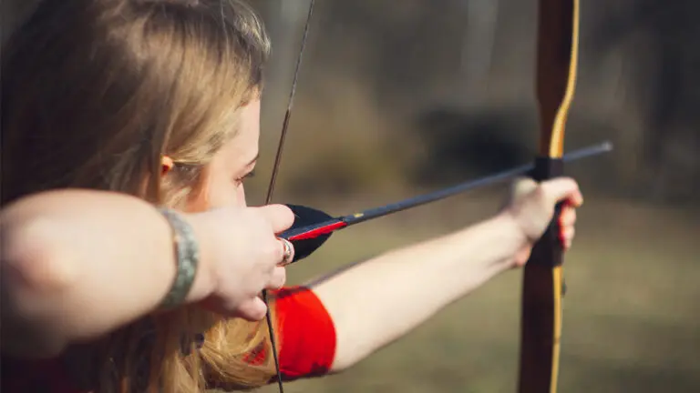 A girl pulling back an arrow during archery