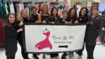 Group of Naperville moms holding a Dress Up 203 banner as they prepare donated prom dresses for Naperville 203 students