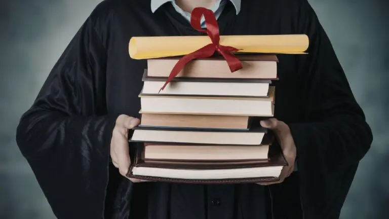 person in graduation gown holding stack of books and tied diploma at the top