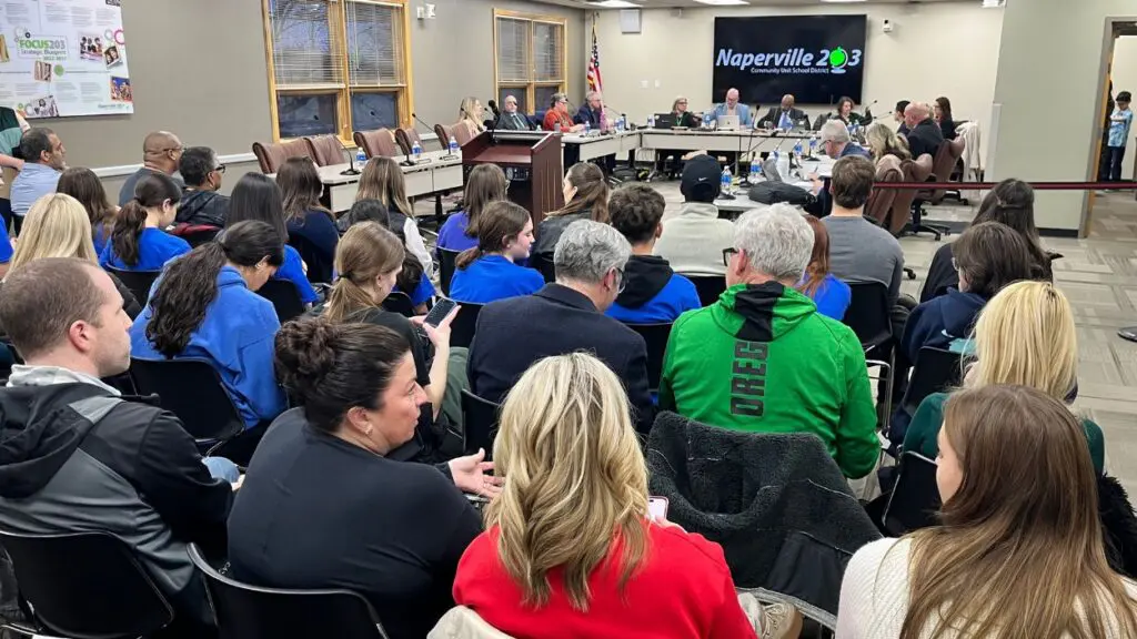 Wide shot of public seated watching Naperville 203 board meeting