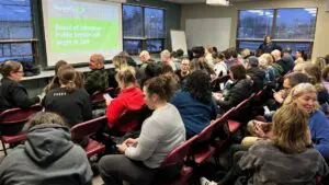 Community members seated in overflow room.