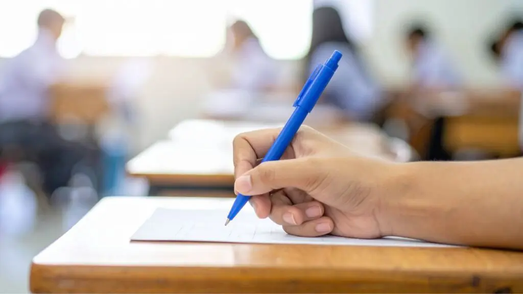 Close up of student's hand holding pen writing on some paper