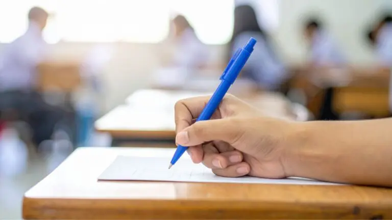 Close up of student's hand holding pen writing on some paper