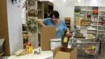 A vendor at Painted Tree Boutiques packs up her booth, putting items into a box, amid the store's closure.