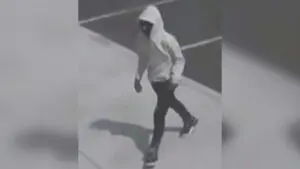 A man wearing a white sweatshirt and black pants is pictured walking.
