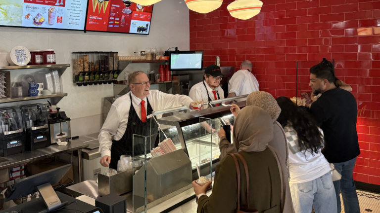 An Oberweis employee hands ice cream to a customer
