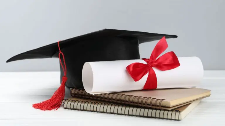 Diploma and graduation hat sitting on notebook