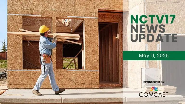 Construction worker carrying boards near wood frame of house