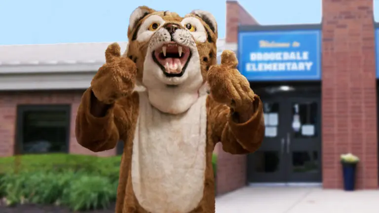 Bobcat mascot giving two thumb up in front of Brookdale Elementary School