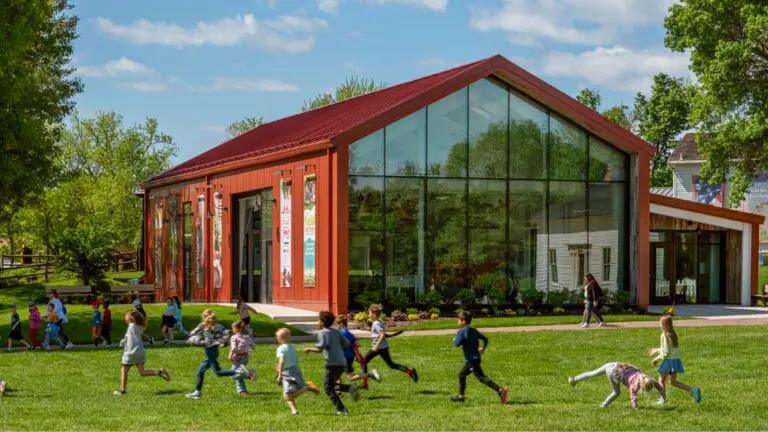Children play in the grass in front of the Benck Family Ag Center at Naper Settlement.