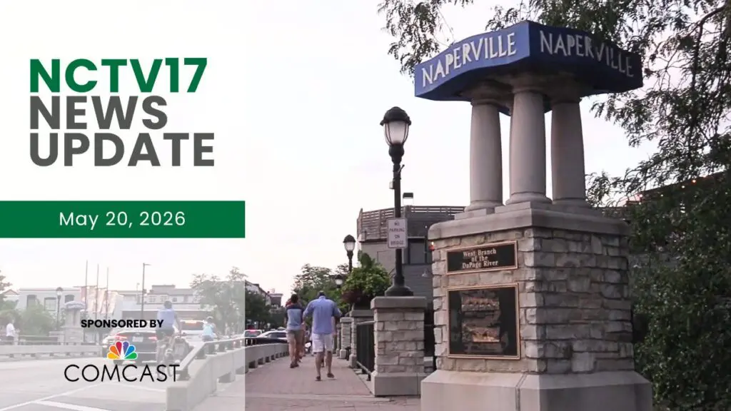 A shot of the blue Naperville sign in downtown Naperville with people walking on a nearby sidewalk.