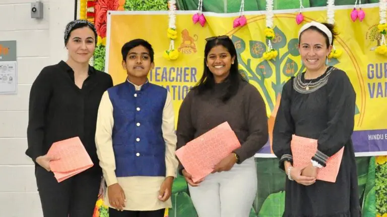 Naperville-area teachers stand alongside a student while holding a pink gift during the Naperville Guru Vandana event for Teacher Appreciation Week.
