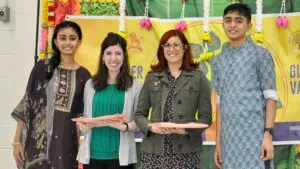 Two teachers stand alongside their two students after collecting a gift during the Guru Vandana event.
