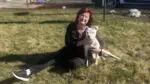 Angel Dog Alliance founder Teresa Ryan sits in the grass with a dog.