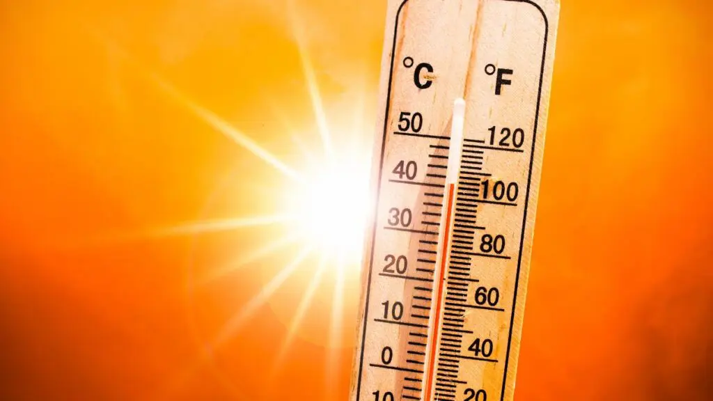 Thermometer showing temperature over 100 degrees in front of an nimage of the sun