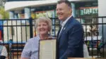 Executive Director of the Fry Family YMCA in Naperville stands with mayor Scott Wehrli with a proclamation in celebration of her 43-year career with the YMCA ahead of retirement