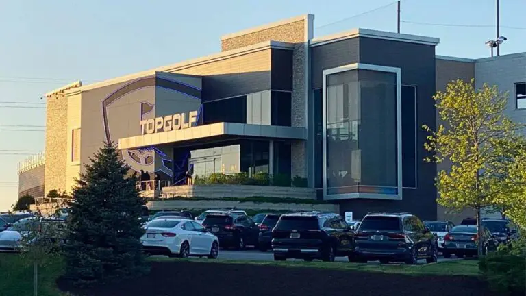 Wide shot of Naperville Topgolf with parking lot and cars visible