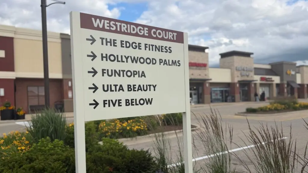 Close up of sign for businesses at Westridge Court with blurred shopping center in background