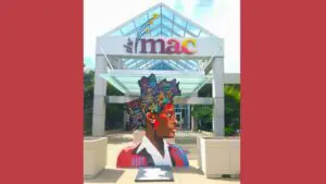 Walking with Giants sculpture in front of a sign for the MAC at COD
