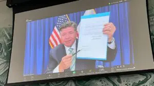 Gov. J.B. Pritzker is seen on Zoom holding up House Bill 4438 during a virtual bill-signing ceremony Thursday.