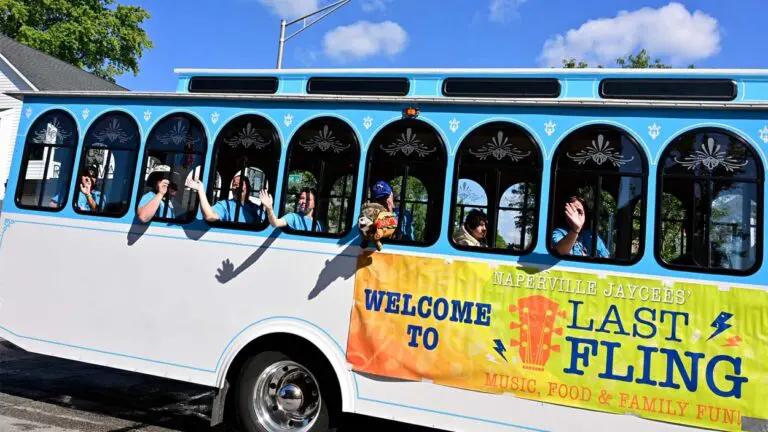A group of Naperville Jaycees hang out the window of the Naperville Trolley during a Labor Day Last Fling Parade in Downtown Naperville.