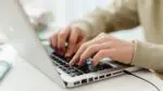 Close up of person's hands typing on computer keyboard