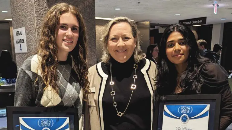 Two students hold their Youth Service Awards with Nina Menis, the executive director of KidsMatter.