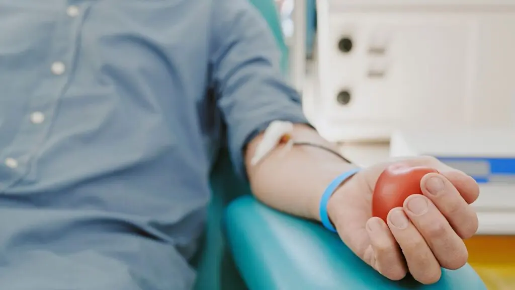 Close up of man holding squeeze ball with blood drawing tubes in arm