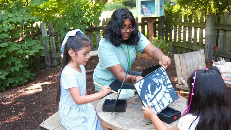 Two children work with an adult on water painting in a Basics-inspired garden at The Morton Arboretum.