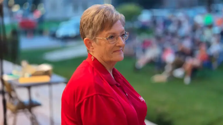 Dianne Hutchison on the stage of the community concert center with the audience in the background.