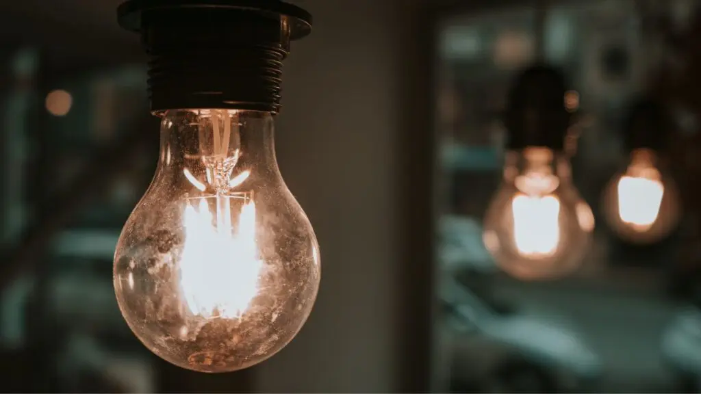 Close up of light bulb lit up with two other light bulbs in the background