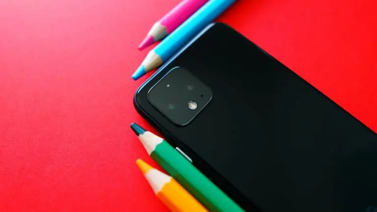 Cellphone and some colored pencils against a red background