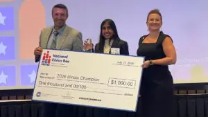 Illinois Civics Bee state champion Astha Savalia of Naperville receives her winnings for the competition from Jimmy Clayton, president of the Illinois Chamber of Commerce, and state finals competition moderator Kelly Pautler Edwards of State Farm