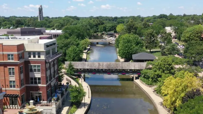 Drone shot of downtown Naperville looking at Water Street buildings, DuPage River, bridges, and Moser Tower