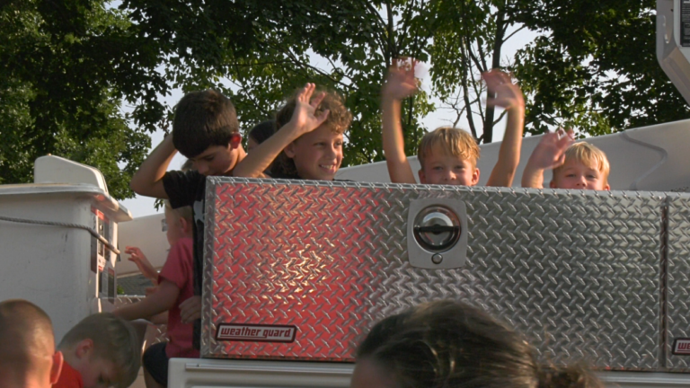 kids wave from city utility truck