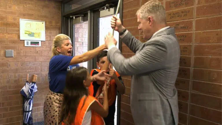 Superintendent Price ringing the Brookdale bell with Principal Schmid and two students
