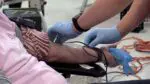 A person holds out their arm to give blood at a donation event