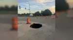 An open sinkhole surrounded by orange traffic cones